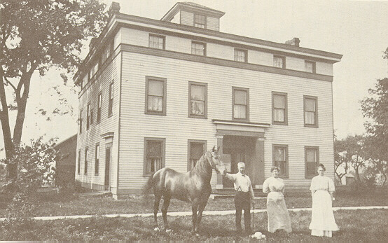 Two women, a man, and a horse stand in front of the Empire House.