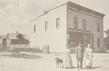A family and their dog stand in front of a building.