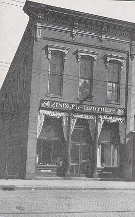 A two story building with a sign reading "Zindler Brothers" between the two levels of window panes.