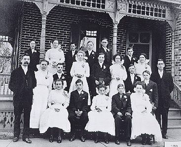 A confirmation class sits grouped for the photo on the steps of a porch.