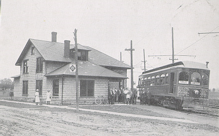 People mingle between the depot and a trolley car