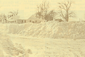 Snow piled high along the roadside in front of a house.