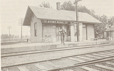 A man stands in front of the Stony Ridge depot, looking over the railroad tracks.
