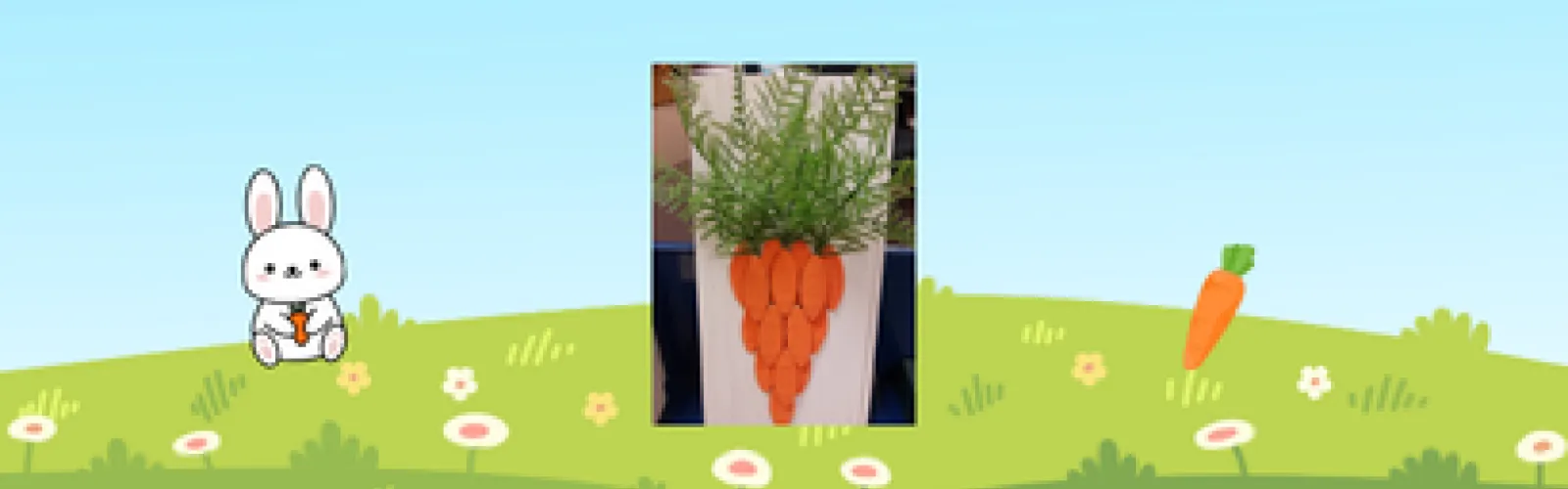 A photo of this month's craft sits in front of a background of a grassy field, next to a cartoon rabbit and carrot.