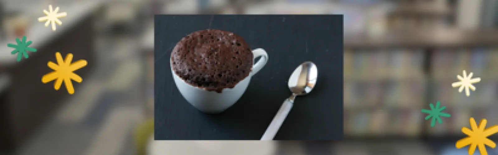 A photo of a mug cake on a countertop with a spoon beside it, with graphics of stars beside that.