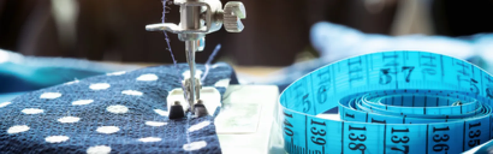 Fabric sits inside a sewing machine with measuring tape in view.