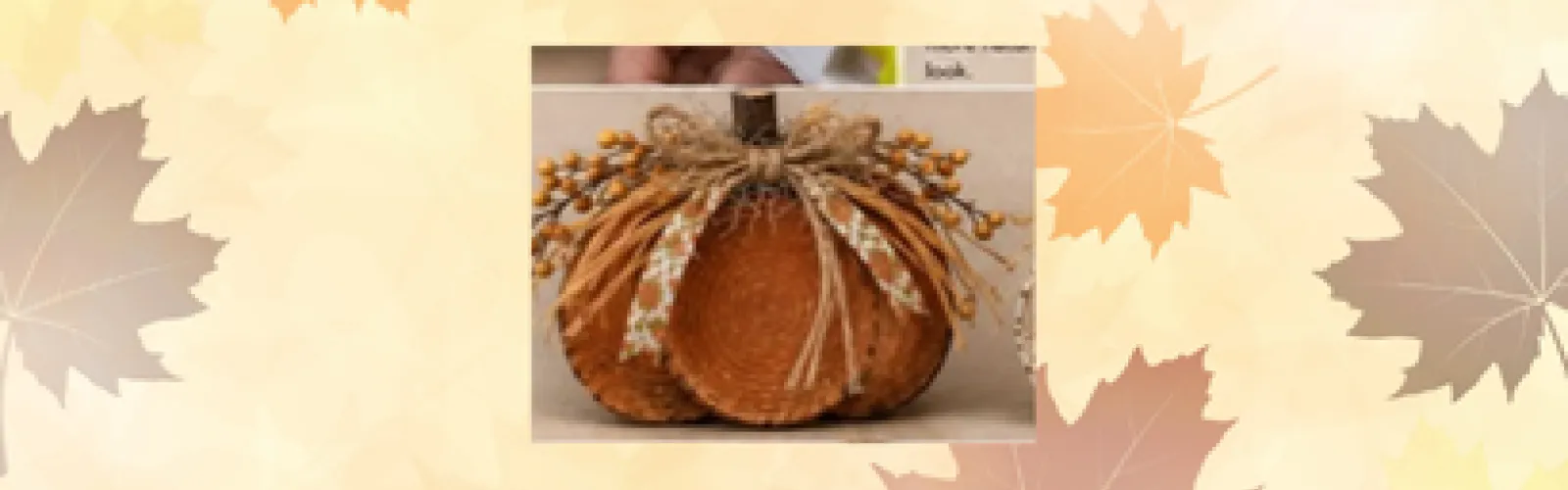 A pumpkin made of wooden blocks sits in front of a fall-themed background.