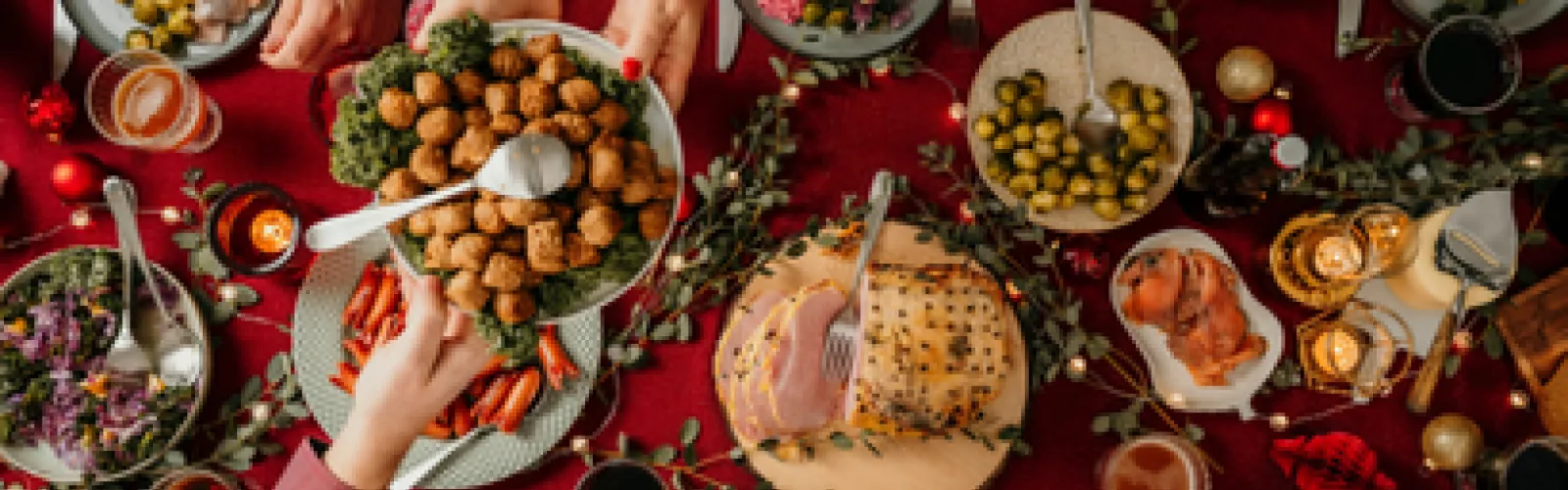 A top-down view of a table with an assortment of food and various people preparing it.